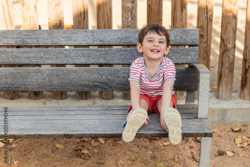 Happy smiling child sitting on park bench