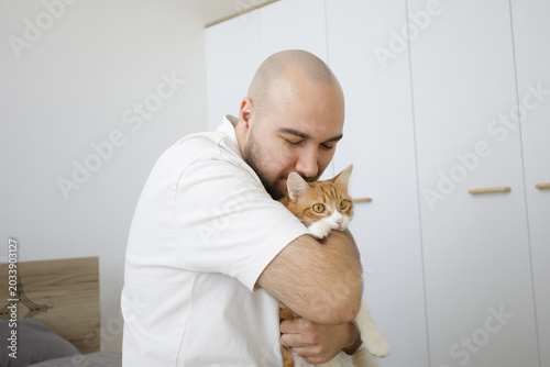 Portrait of man holding fluffy cat pet and having fun together at home