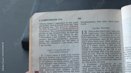 Holy Bible open up to the book of 2 Corinthians of the new testament, zooming into Chapter 12 verse 9 on God’s grace sufficiency. New Revised Standard Version