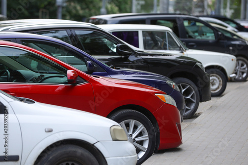 Row of parked cars in a city street parking lot.