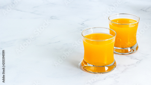 Fresh Orange Juice in Two Glasses on White Marble Background with Copy Space