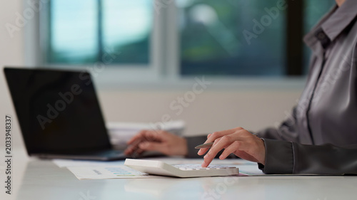 Bilde på lerret Person using calculator and laptop for accounting in modern office