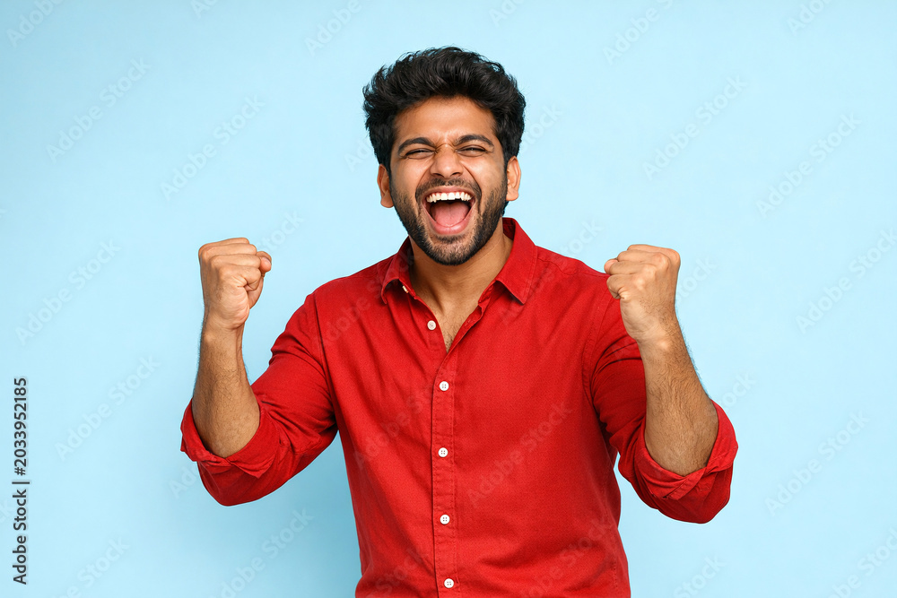 Fototapeta premium Happy Indian man in red shirt smiling and cheering