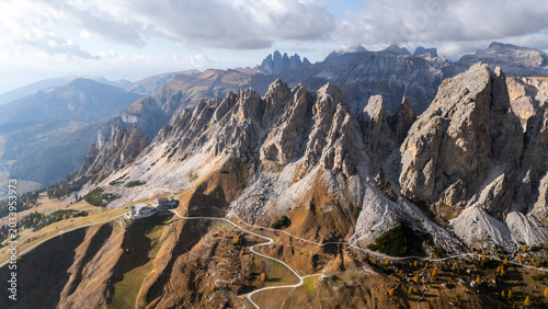 Aerial view of the jagged peaks of Gardena Pass with winding roads and autumn colors in the Dolomites Corvara, Trentino-Alto Adige, Italy.