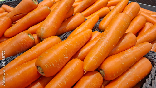 Fresh organic carrots stacked in a rustic woven basket at the local grocery store market