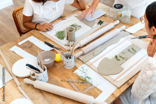 Friends enjoying ceramics workshop, creating handmade pottery with natural elements