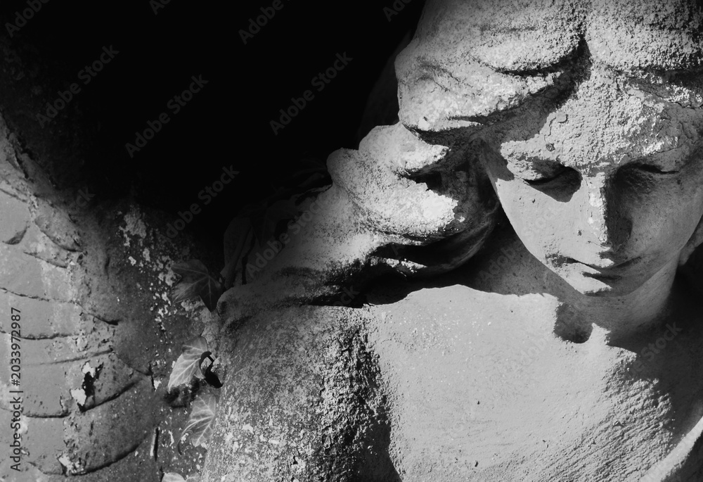 Obraz premium Sad angel statue in dramatic black and white composition.