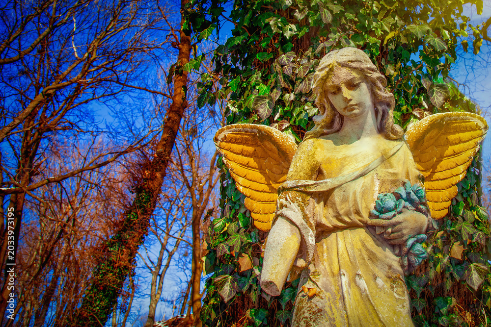 Obraz premium Angel of hope statue with golden wings under deep blue sky. Copy space for text or design.