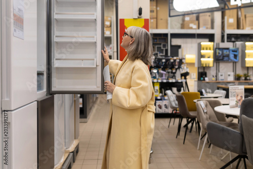 Woman choosing a new refrigerator in a home appliance showroom