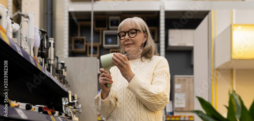 Senior woman examining a hand blender or whisk in a home goods store