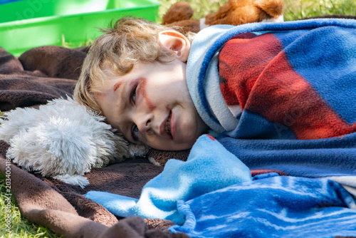 Tableau sur toile A sulking boy - Neurodivergent child, lies on a blanket in the garden