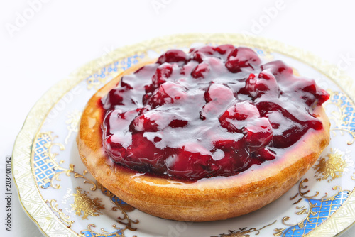 Round cherry cake with fresh cream and jelly on white table