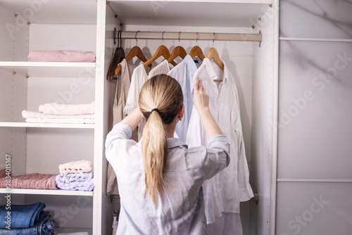 Foto Woman organizing closet, sorting clothes carefully