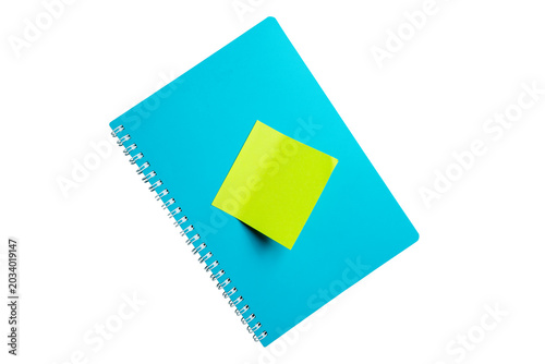 High-angle shot of a vibrant blue spiral-bound notebook with a bright green adhesive note attached to the center, isolated on a solid black background. Perfect for office or school themes