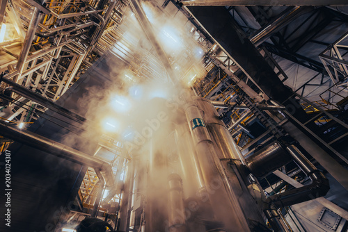 Photos Upward view of industrial pipes with steam and steel structures