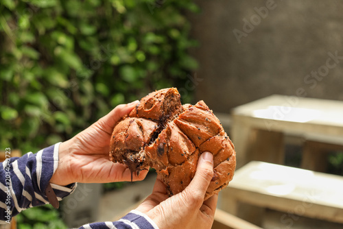 Hands hold split, golden-brown bread with moist interior