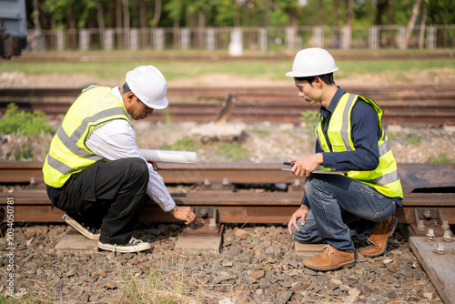 Engineers Inspect Railway Tracks on Construction Site with Safety Gear