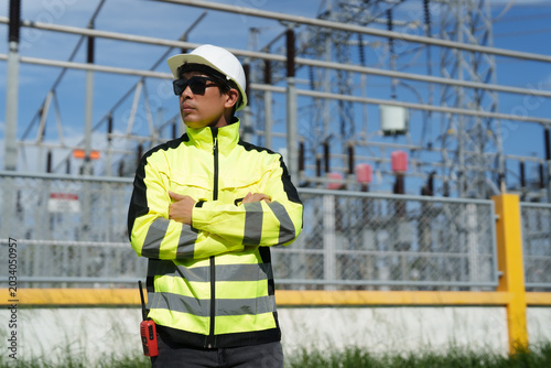 Cuadro en lienzo Asian electrical engineer standing confidently with arms crossed, wearing safety