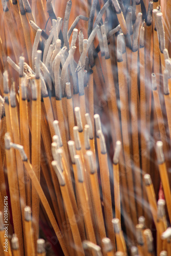 Close-Up Of Burned Incense Sticks With Smoke Rising In A Temple Ritual Offering