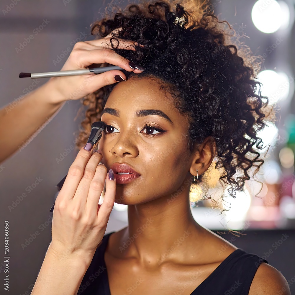 Fototapeta premium A woman having her makeup applied by an unseen person