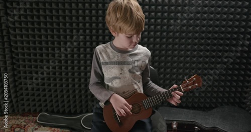 Boy Play Music on Ukulele Instrument in Home Studio. 4K 10-bit