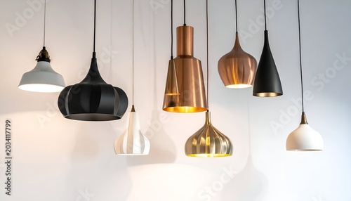 A collection of modern pendant lights of various shapes and finishes against a white wall
