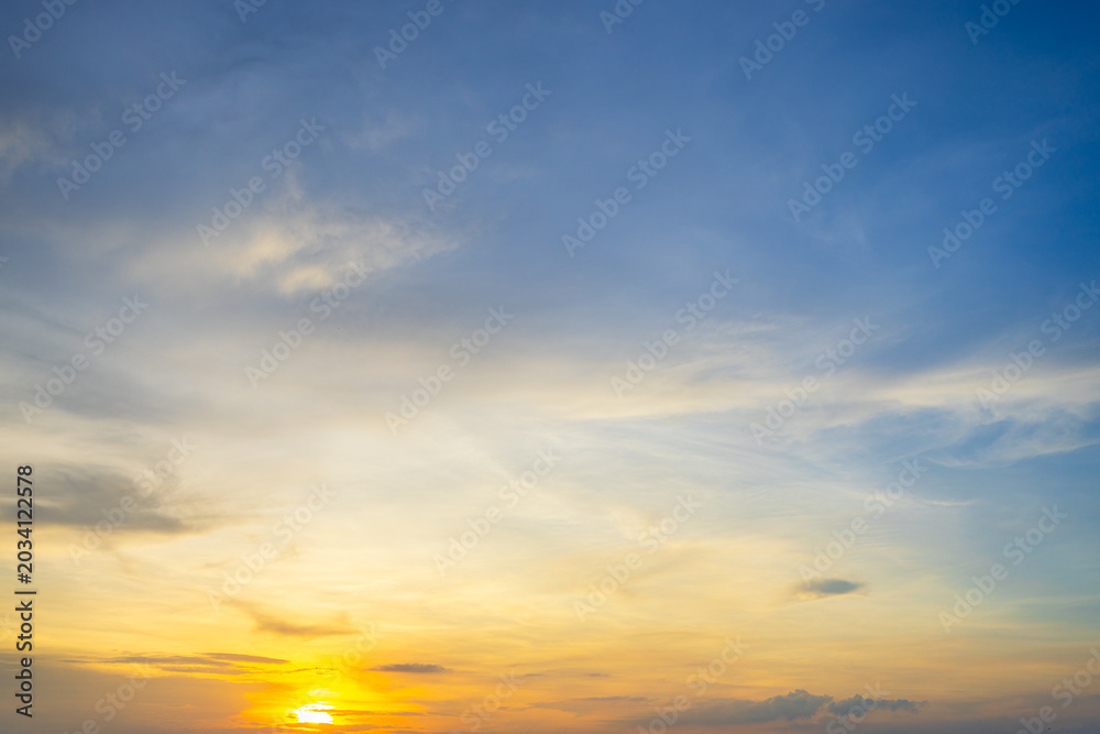 Fototapeta premium A breathtaking sunset sky with soft, wispy clouds and a vibrant golden glow casting a warm light over the horizon.