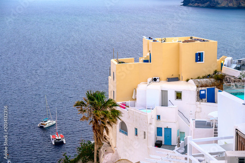 Fotografia Yellow house and boats below Oia at dusk