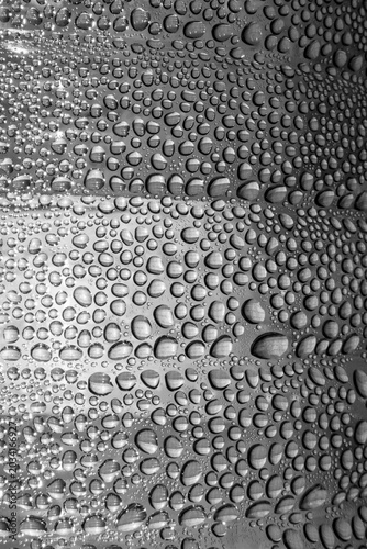 Fotografi Monochromatic macro shot of dense water droplets on a surface, creating a rhythmic and complex abstract texture with sharp highlights and reflections