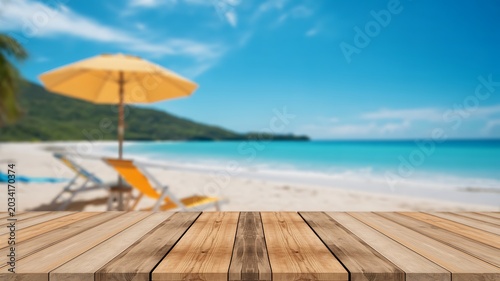 Wooden table product display photo background with blurred tropical beach and umbrella