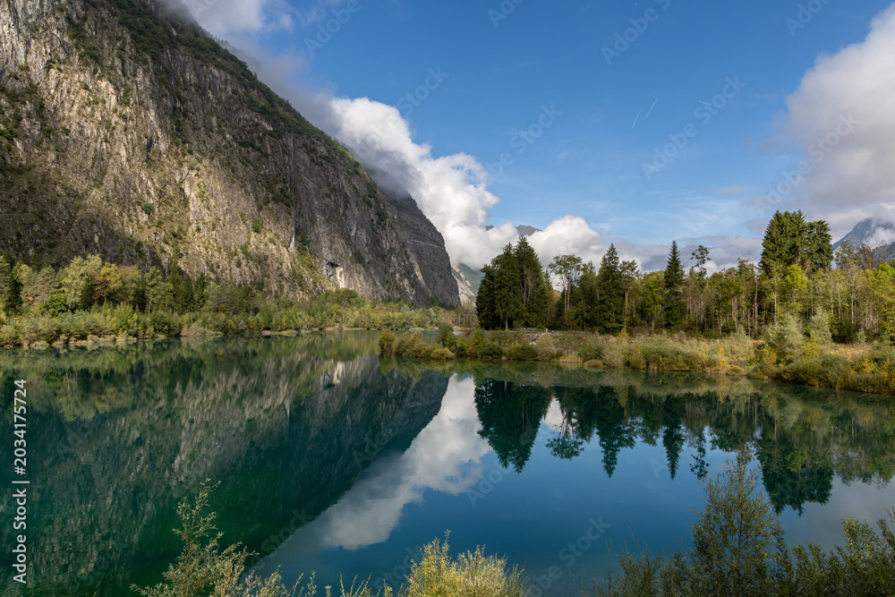 Naklejka premium Peaceful Alpine Lake Buclet surrounded by mountains under a blue sky and few clouds in the French Alps, Isère