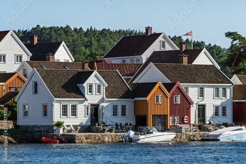 Local coastal traditions with coastal wooden houses, tiled roofs and compact waterfront neighborhood along the harbor in southern Norway for regional travel and Nordic culture