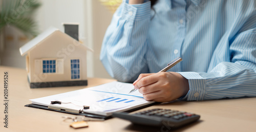 Businesswoman reviewing mortgage and real estate documents while talking on phone, representing home loan planning, property investment, financial analysis, and housing finance management.