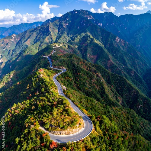 Winding Mountain Road Curving Through Lush Green Peaks Under Blue Sky