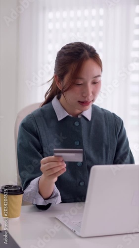 young Asian businesswoman hold credit card shop online using laptop computer for ecommerce payment transaction purchase digital banking home office concept