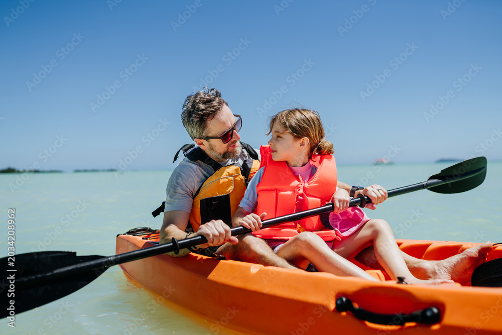 Naklejka premium Father kayaking with daughter on calm sea during family summer vacation.