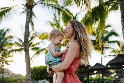 Foto Mother embracing her little daughter in tropical beach resort.