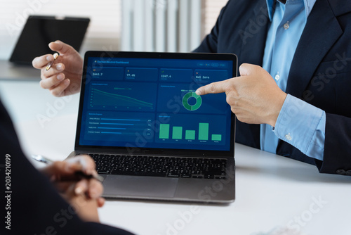Canvas-taulu Business people collaborating, reviewing financial data dashboard on a laptop, d