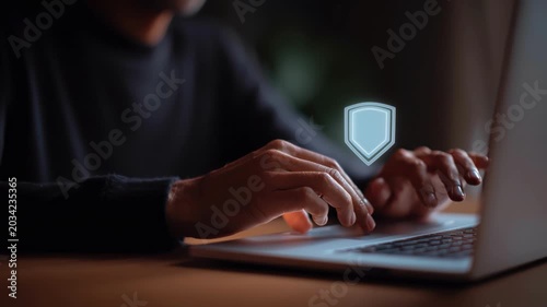 Hands typing on laptop with shield hovering above keyboard, warm desk lighting and focused atmosphere secure login overlays, authentication visuals and fingertip gestures on keys, scenes portray
