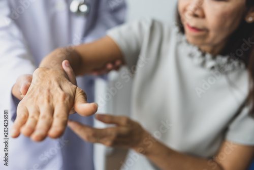 Fotografie Doctor assesses senior woman's wrist and arms mobility and pain during clinical consultation, evaluating joint function and possible arthritis or injury in a healthcare
