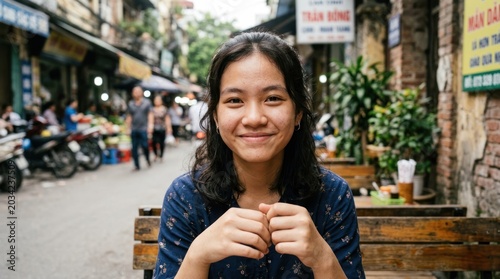 A young woman sitting on a bench in a bustling street market, smiling warmly.