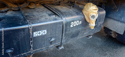 Gas tank of a truck with visible markings and a protective cover, showcasing a rugged design suitable for heavy-duty vehicles in an outdoor setting