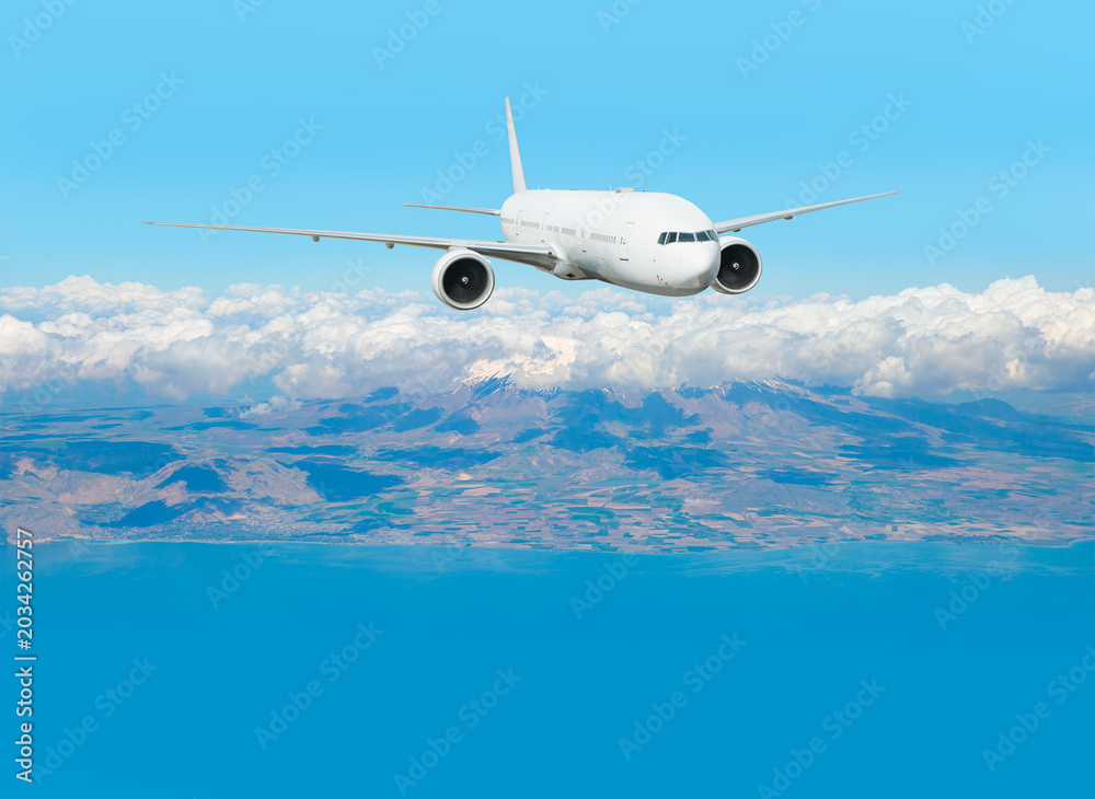 Naklejka premium A passenger plane takes off over the coastal city and mountains.