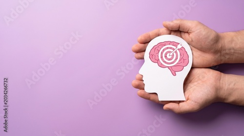 Mental focus and goal achievement concept, human hands holding paper head with brain and target icon, psychological health and mindfulness