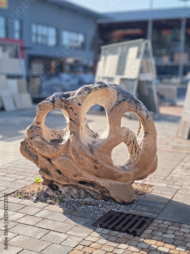 Weathered Wooden Statue Featuring Round Openings In Sunlight