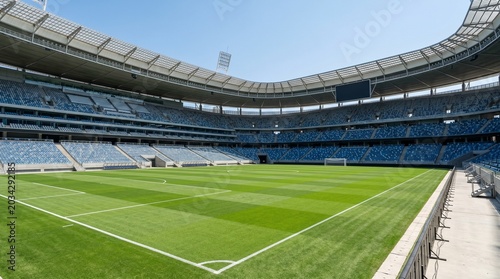 Empty modern football stadium with green grass pitch and blue seats
