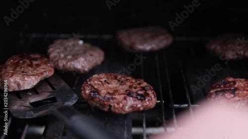 Juicy beef burger patties grilling on barbecue, close up of meat cooking on hot grill with char marks and smoke