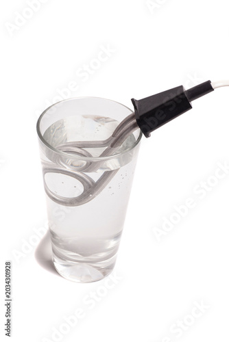 Immersion electric water heater in a glass of water isolated on white background