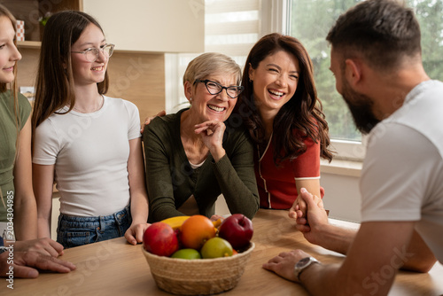 Фотография Joyful three generation family sharing relaxed home conversation moment