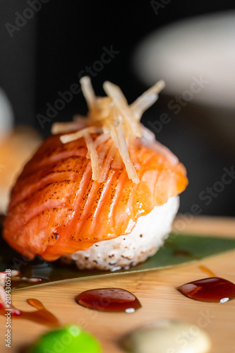 Photos Seared salmon temari sushi with ginger on a wooden board, close up view